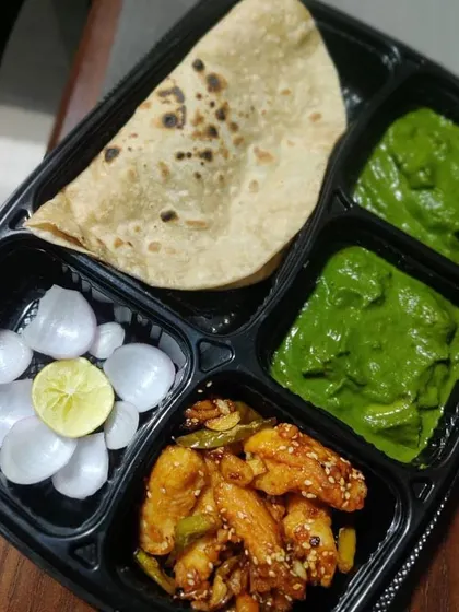 A simple yet satisfying North Indian meal box with chapati, palak paneer (spinach and cottage cheese curry), honey chili potatoes, and pickled onions.