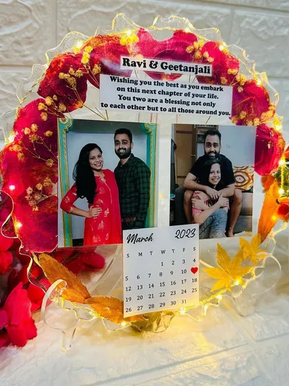 This round, 10-inch tabletop frame features preserved red flowers, two photos, and a custom calendar marking a special date. The LED lights add a warm glow.