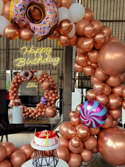 Fun and playful themes are my specialty. This donut and candy-themed birthday decoration uses a rose gold balloon arch with whimsical donut and candy foil balloons, plus a custom neon sign for a sweet celebration.