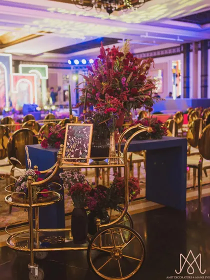 A stylish gold bar cart adorned with vibrant floral arrangements, serving as both a functional and a beautiful decor piece for the sangeet night.