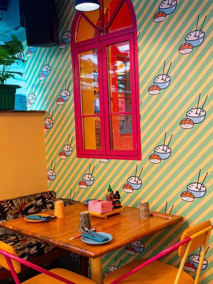 A simple table setting at The Fatty Bao against a backdrop of patterned wallpaper and a brightly colored window frame. This shot focuses on the fun details that make up the restaurant's visual identity.