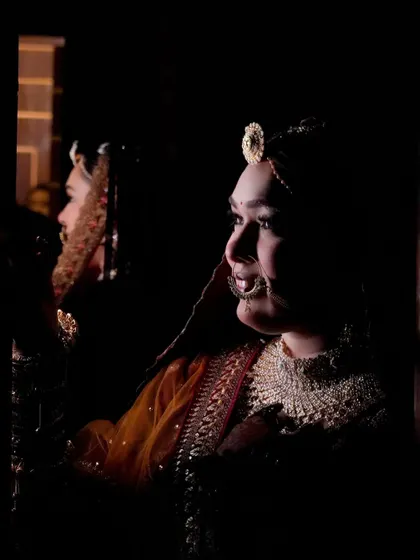 A dramatic, low-key portrait of the bride, her face partially lit, creating a sense of mystery and elegance.