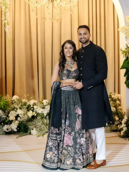 A classic portrait of a stunning couple, Nikki & Avin, at their reception. They stand against a backdrop of white flowers, exuding elegance and happiness.