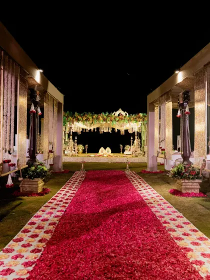 A grand wedding aisle covered in a carpet of red rose petals, leading to a magnificent mandap. This sunrise wedding was designed to feel both traditional and surreal, set against the backdrop of the Bay of Bengal.