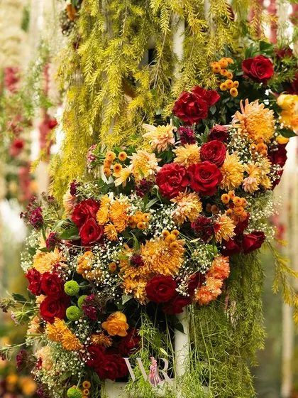 A lush floral arrangement on the mandap pillar, combining red and orange roses and chrysanthemums. These vibrant colors brought warmth and energy to the sacred space.