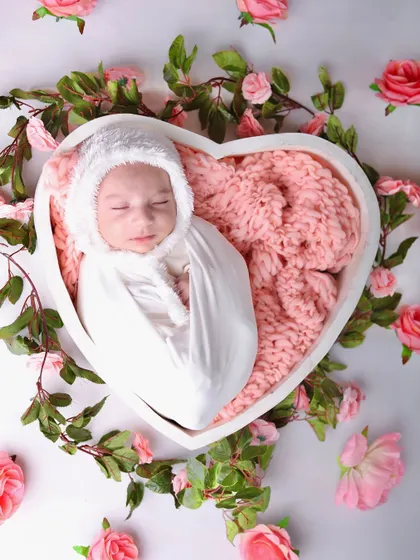 A top-down view of the baby nestled in the heart bowl, encircled by a ring of beautiful pink roses and green leaves.