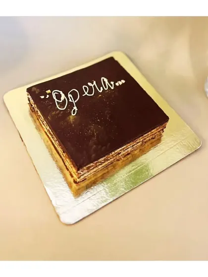 The classic French Opera cake is a masterpiece of precision. It has thin layers of almond sponge soaked in coffee syrup, layered with coffee buttercream and chocolate ganache, and topped with a chocolate glaze. Elegant, rich, and timeless.