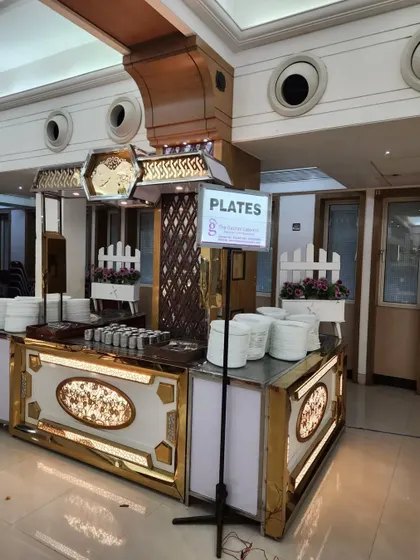 This dedicated station for plates is part of a larger, ornate buffet setup. The design ensures smooth guest flow and adds to the overall aesthetic of the event.