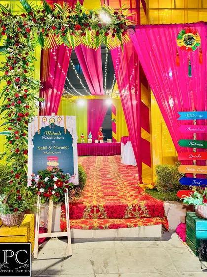 A grand entrance for a colorful Mehndi night. I used bright pink and yellow drapes, a floral arch, and a personalized welcome sign to greet the guests.