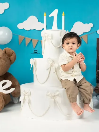 A thoughtful pose sitting on the prop cake. This classic portrait is a wonderful way to remember their first birthday.