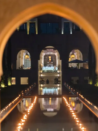 A view through the arches of the Oberoi, Marrakech, looking onto the palatial ivory-and-gold reception dinner. The reflection in the water channel, lined with candles, doubled the magic of the evening.