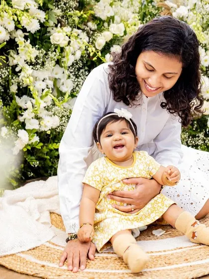 A happy baby girl enjoying a moment with her mom against a wall of flowers. This black and white photo feels so classic and joyful.