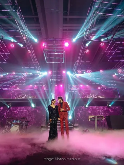 The couple takes the stage for their Sangeet entry, surrounded by dramatic lighting and low-lying fog, creating a truly cinematic moment.