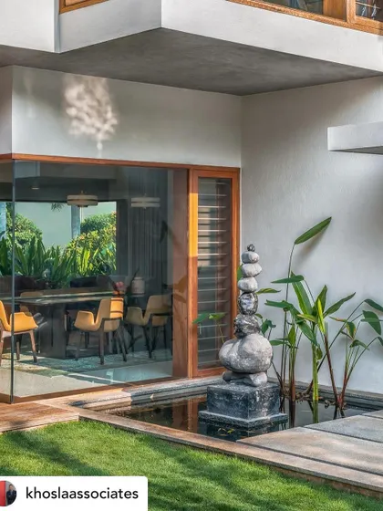 A tranquil water body with a stone sculpture, situated next to a glass-walled dining room. The placement ensures that the calming presence of water and art is a part of the daily dining experience.