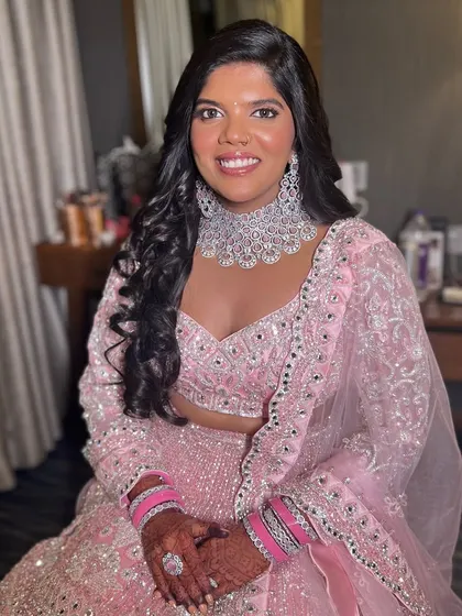 A stunning reception look in a pink lehenga. The makeup is glamorous and sophisticated, with a focus on her beautiful diamond jewelry.