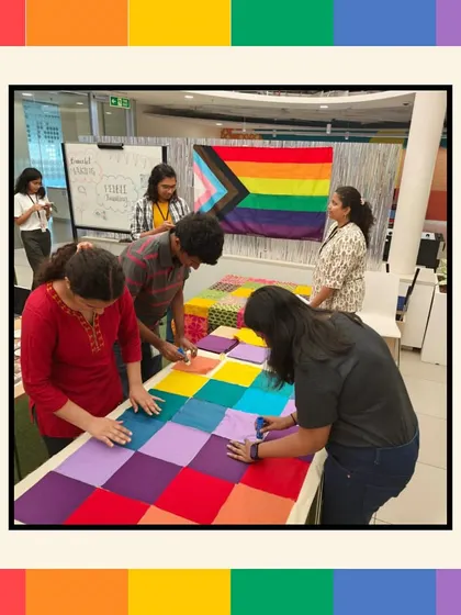 A wider view of the Pride quilt making station at Intuit, with the Pride flag in the background. We create an inclusive and celebratory atmosphere for our D&I workshops.