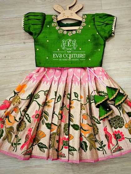 A lovely Kalamkari lehenga with a bird and flower motif. The green blouse has delicate embroidery, and the set is finished with cute bow-shaped tassels.