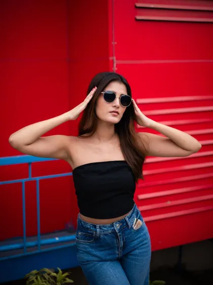 A classic fashion portrait against a bright red wall. The model's pose and sunglasses give this shot a cool, effortless style.