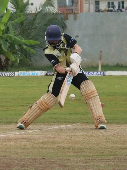 A batter plays a defensive shot on the front foot.