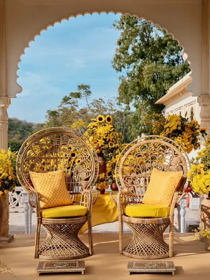 Peacock chairs set for the bride and groom, surrounded by an abundance of sunflowers and yellow lilies, creating a picture-perfect Haldi spot.