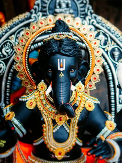 A full-frontal shot of a stunningly detailed black Ganpati idol, showcasing the intricate jewelry and serene expression. This image highlights the incredible craftsmanship that goes into creating these masterpieces for the festival.