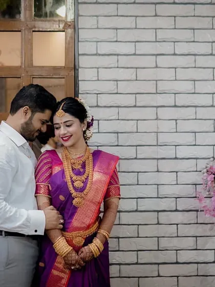 An intimate portrait of the couple after their engagement, the groom in a sharp white shirt embracing his bride in her traditional purple saree.