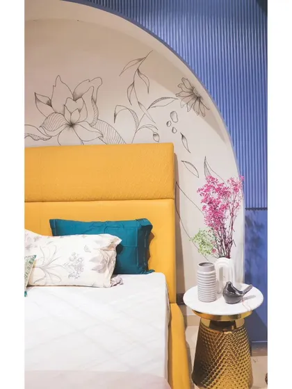 A detail shot of the bedside, showing the elegant floral mural and a chic gold side table.