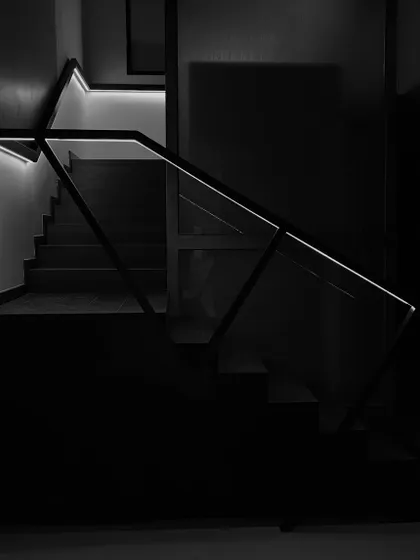 Another perspective of the illuminated staircase, highlighting its sharp, geometric lines against the darkness. This detail showcases our minimalist approach to creating impactful design features.