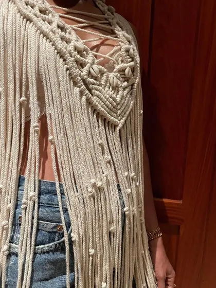 The details are what make a piece special. This close-up shows the intricate knotting and cowrie shell embellishments on the neckline of my macrame cape, adding a touch of the ocean to this bohemian design.