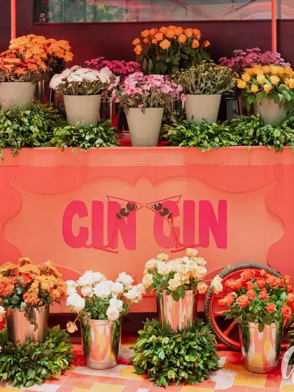 A custom 'Cin Cin' bar cart serves as both a functional drink station and a beautiful decor piece. We filled it with buckets of fresh, colorful flowers, creating an interactive and photogenic corner for guests.