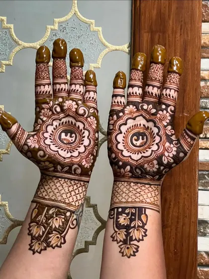 This photo shows the design with the fresh, wet henna paste applied. The initial "E" is clearly visible, and the paste is thick and dark, which is key to a good stain.