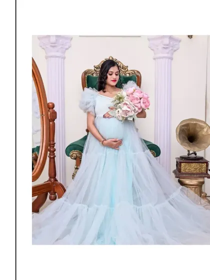 Another elegant portrait on the throne chair. Here, the mom-to-be holds a bouquet of pink and white peonies, adding a touch of softness to the regal setting. The light blue gown looks ethereal and lovely.