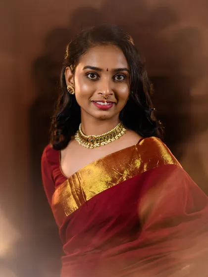 A simple and elegant portrait of a model in a maroon saree with a gold border. The soft, hazy lighting gives this 'Kanmani' inspired shot a dreamy and timeless feel.