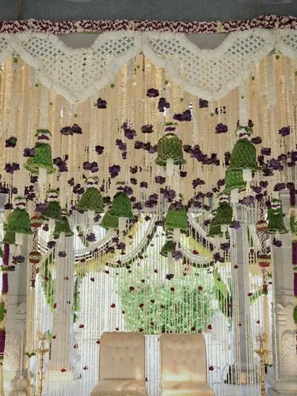A traditional Muhurtham mandap featuring a ceiling of hanging jasmine and purple orchid strings, with delicate bells made of woven coconut leaves.