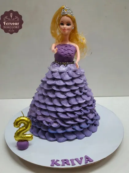 A beautiful doll cake where the cake itself forms the doll's flowing purple gown. The dress is created with piped whipped cream petals, a technique that uses zero fondant for the main design.