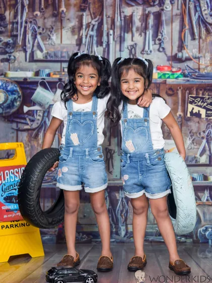 Twin power in the workshop! These two adorable girls in matching denim overalls are having a great time posing with tires in our popular garage-themed set.
