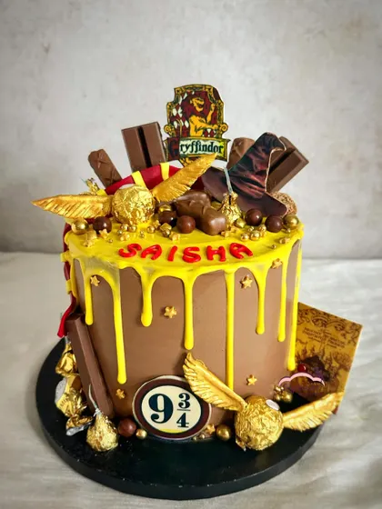 A chocolate lover's dream! This Harry Potter-themed drip cake is loaded with various chocolates, golden snitches, and a Gryffindor scarf for the ultimate magical treat.