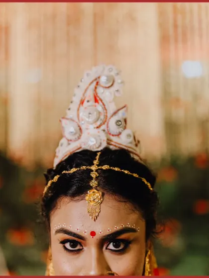 A striking close-up of the Bengali bride, focusing on her traditional 'mukut' and powerful eyes.