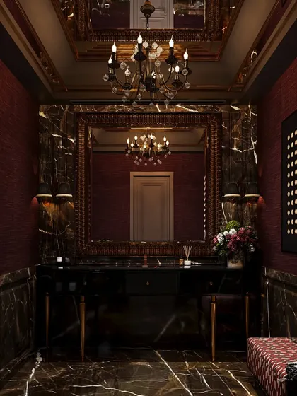This dramatic powder room concept is wrapped in dark, veined marble and deep red textured walls. An ornate mirror and chandelier add to the opulent, moody atmosphere, creating an unforgettable experience.