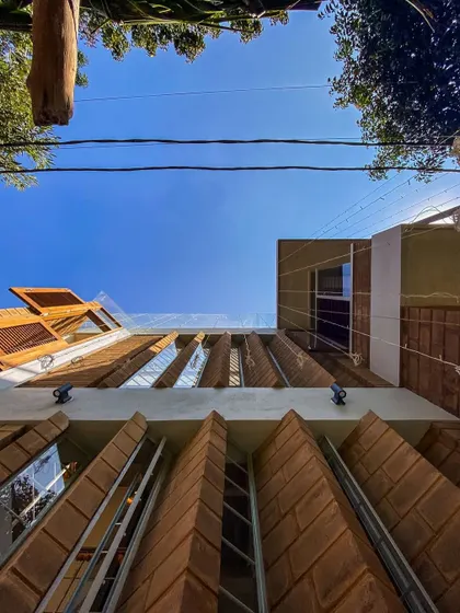 A worm's-eye view of the Divyadarshan home's facade, emphasizing the unique pivoted windows that open up to let in light and air. This design is a key feature for natural ventilation in a tight urban plot.