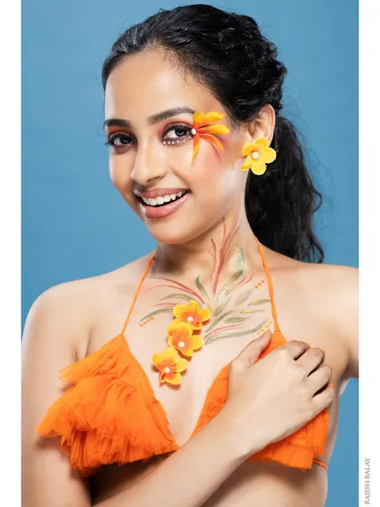 A smiling portrait of a model with a creative floral makeup look.