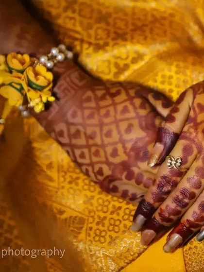 The details matter. This close-up shot focuses on the bride's hands, adorned with intricate mehendi and beautiful floral bracelets, a key part of the Haldi ceremony look.