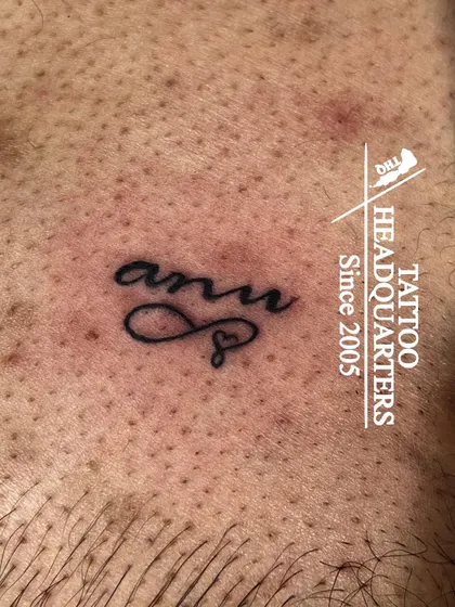 A small name tattoo "anu" with an infinity heart symbol, a delicate and personal piece.