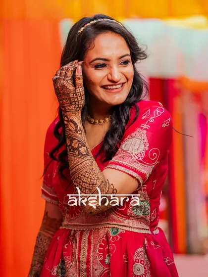 A joyful, candid shot of the bride, Akshara, during her Mehendi ceremony. Her bright smile perfectly captures the happy and festive mood of the day.