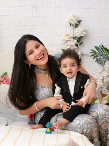 A joyful mother and son portrait. Her radiant smile and his happy expression are the heart of this beautiful image, set against a backdrop of white flowers.