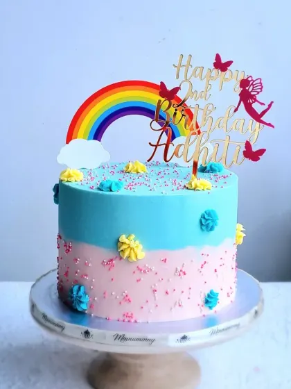 A full view of the two-tone rainbow cake on its stand.