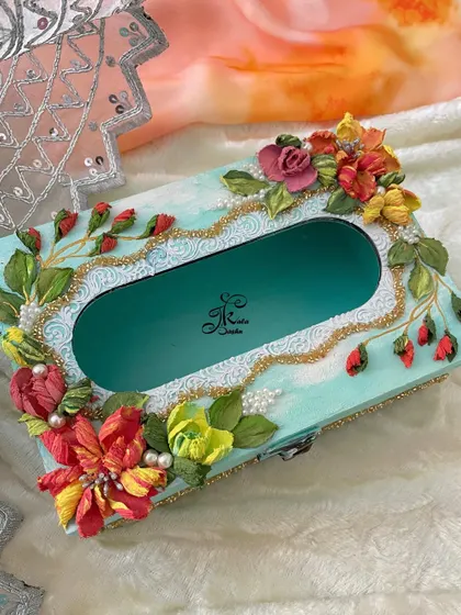 This tissue box has a bright, cheerful feel with its turquoise base and a vibrant mix of multi-colored flowers. The golden liner and pearl details add a touch of luxury.