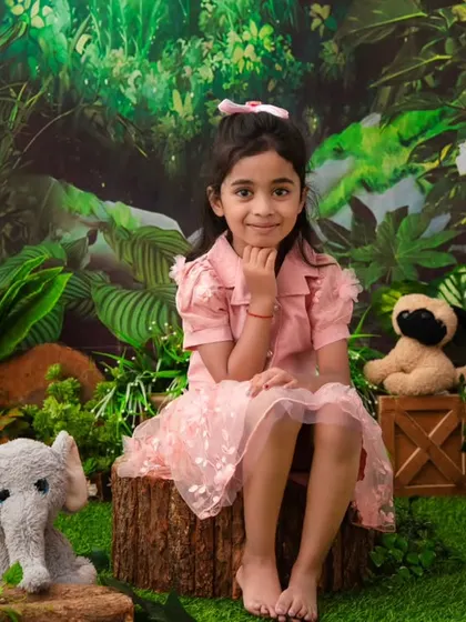 A jungle princess. This older sister poses beautifully in a lush jungle setting, complete with her favorite stuffed animals.