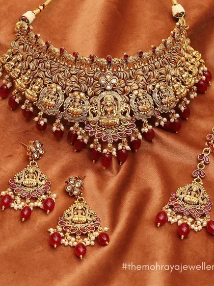 A beautiful temple jewellery set with goddess Lakshmi motifs and red bead drops. This traditional design is available to buy or rent for your special day.