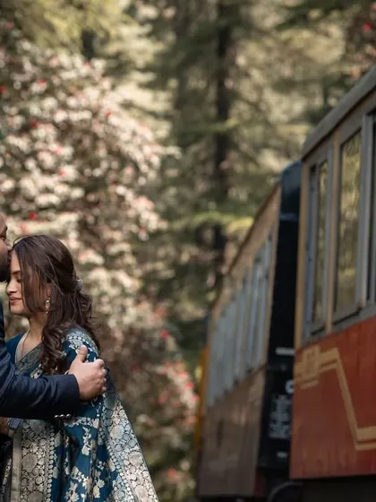 An intimate forehead kiss beside the stationary toy train. This close-up focuses on the couple's tender connection, with the train adding a touch of vintage charm.